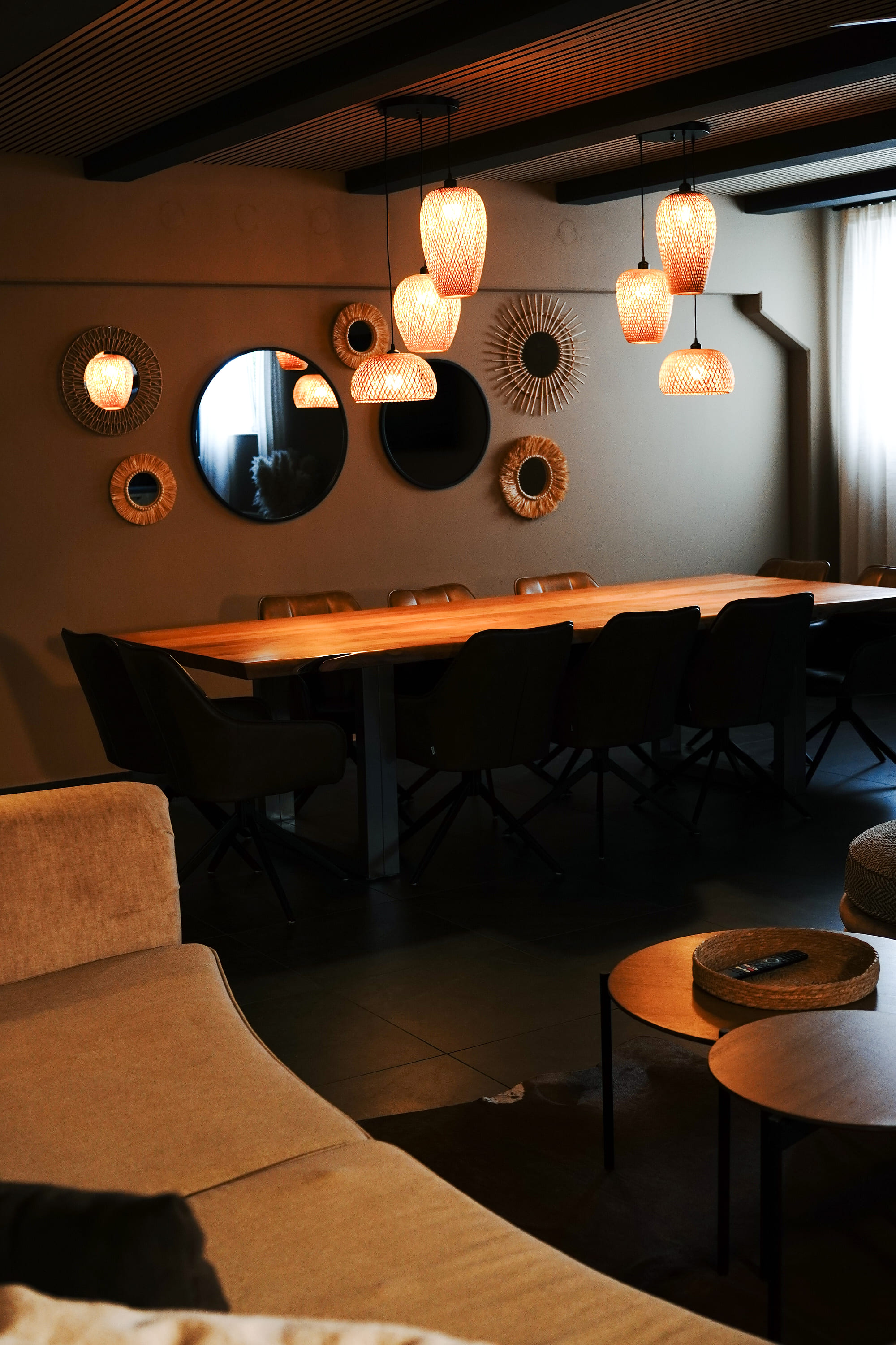 Lounge und langer Esstisch unter Rattan-Pendelleuchten
