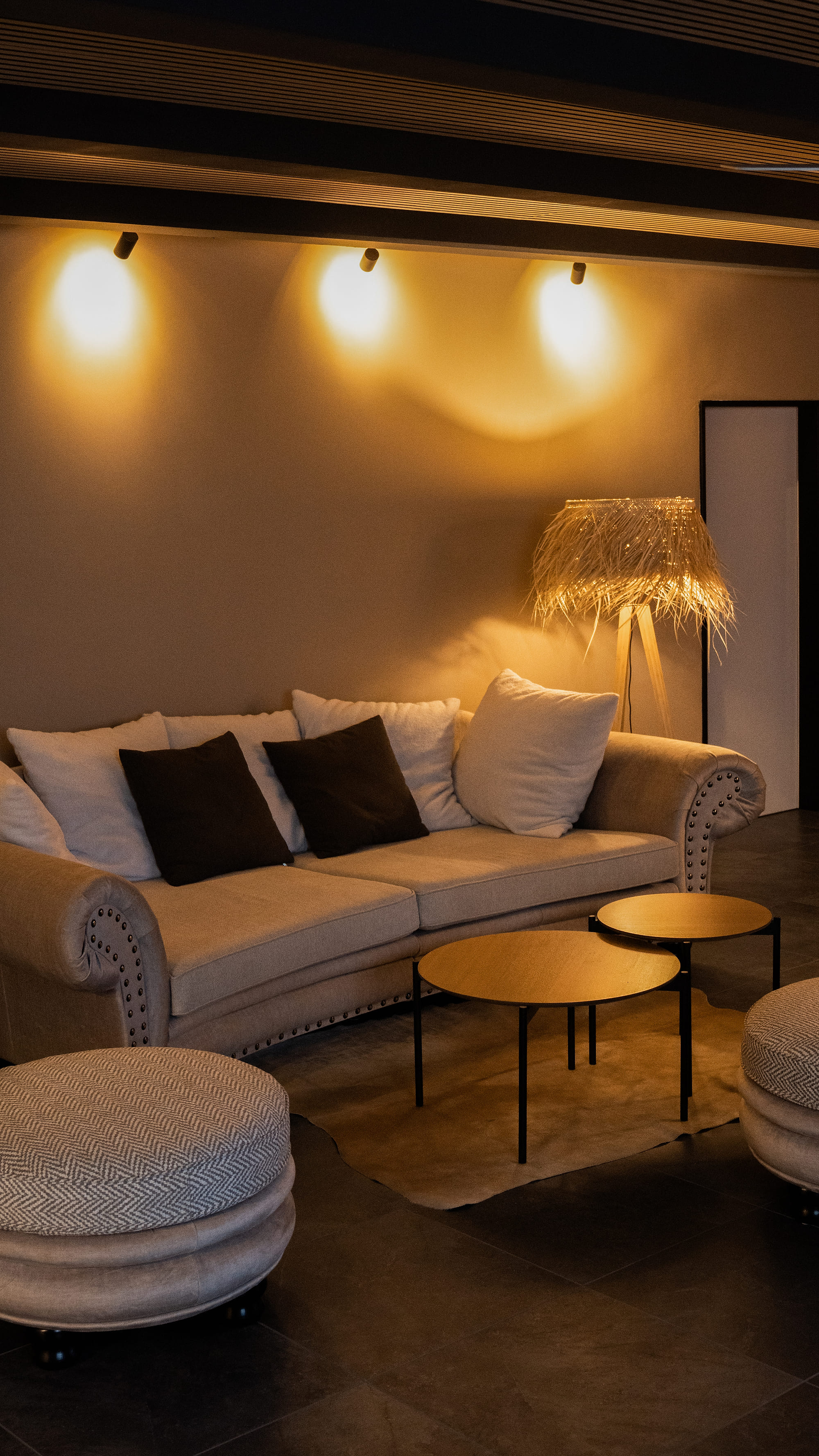 Lounge mit Sofa, Hockern und indirekter Wandbeleuchtung