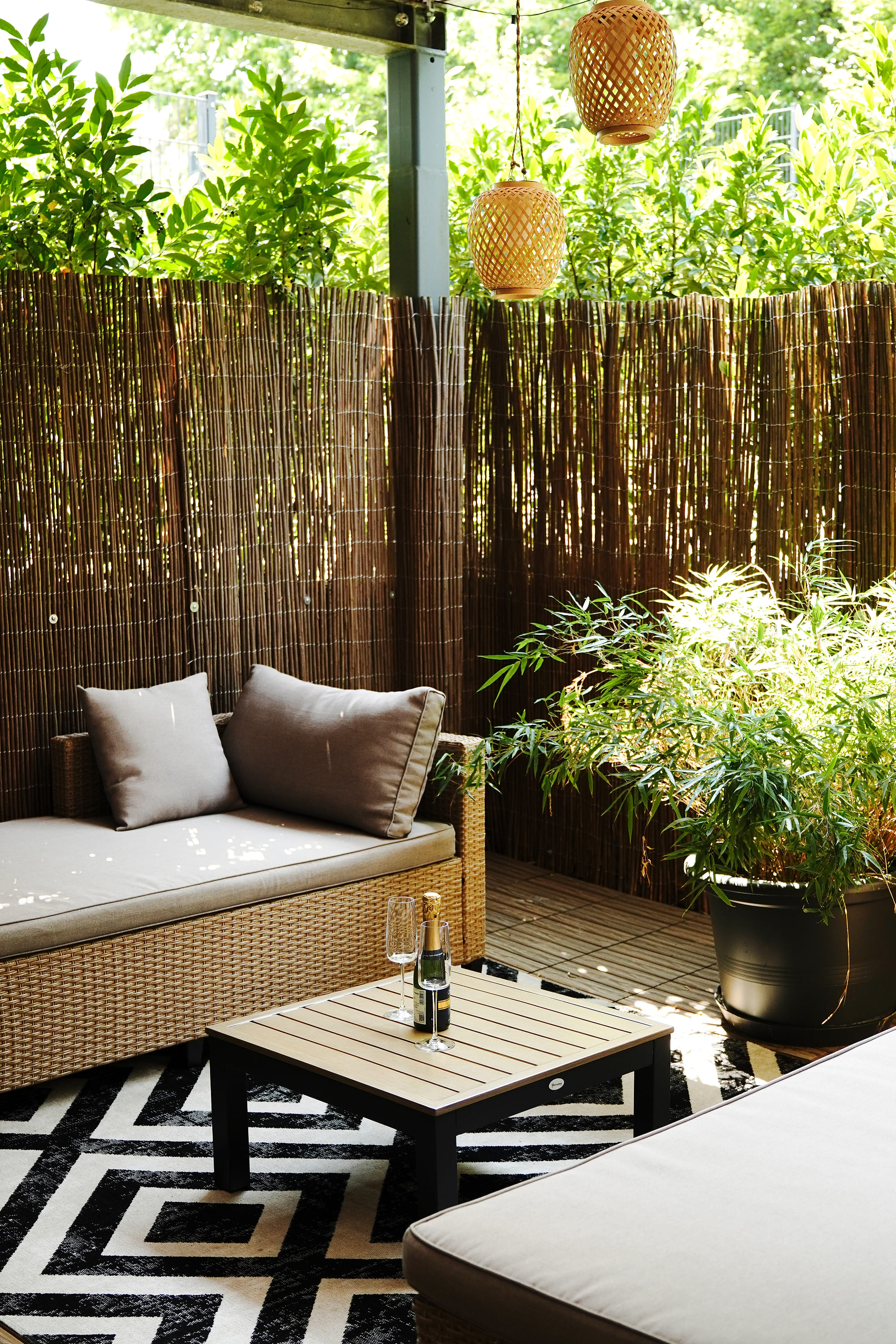 Private Außenterrasse mit Rattan-Lounge, Bambus und Laternen
